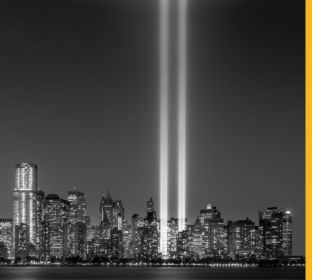 Black and white photo of a city skyline at night with two vertical beams of light shining upward from the center.