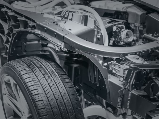 Close-up view of a car’s front wheel, suspension, and chassis components, showing detailed parts of the vehicle's underbody structure.