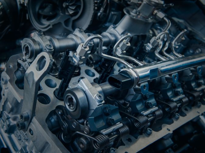 Close-up view of a mechanical engine assembly showing metal parts, fuel injectors, and connecting pipes.