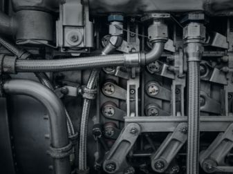 Close-up view of an industrial machine engine with visible metal pipes, bolts, and mechanical components.