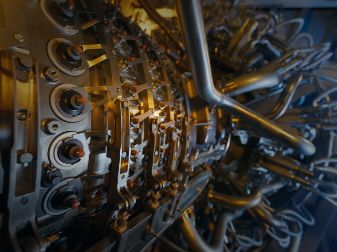 Close-up view of a complex industrial machine with metal pipes, bolts, and cylindrical components, showing intricate engineering details.