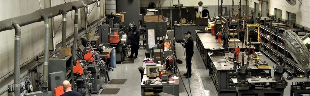A factory workshop with multiple workstations, machinery, tools, and workers performing various tasks in an organized industrial setting.